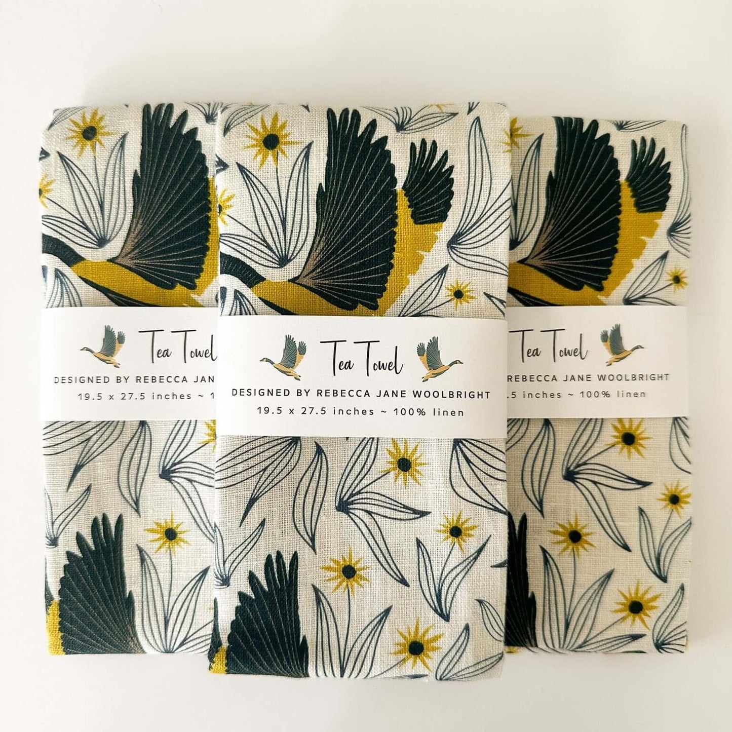 Wingspan Tea Towel - Wingspan tea towel by Rebecca Jane Woolbright shown with matching folded tea towels and belly band packaging