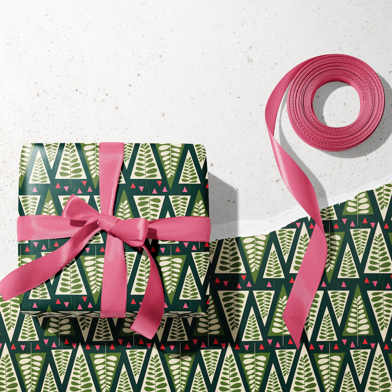 Gift wrap with green pattern and pink ribbon on a white background
