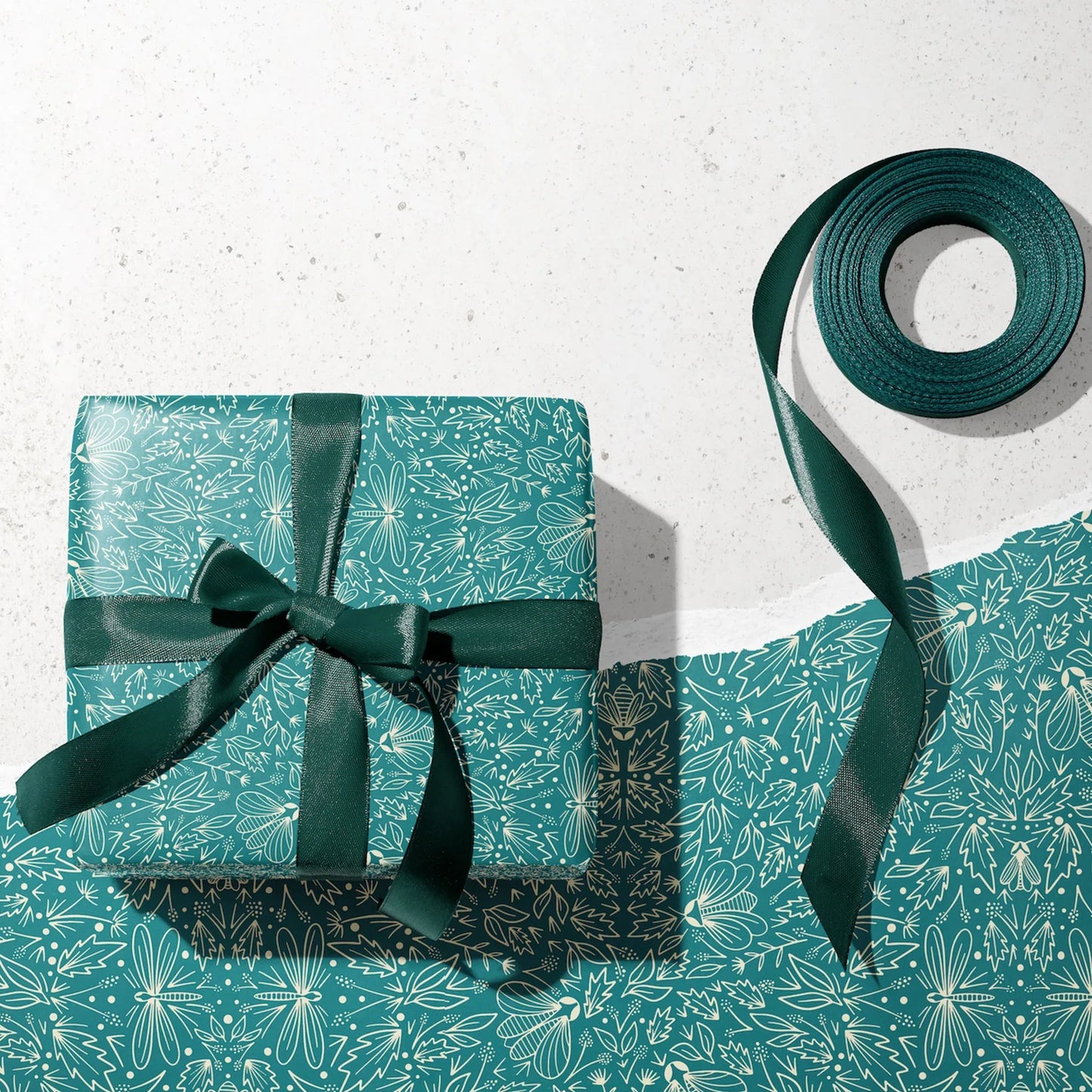 Orion Wrapping Paper - Wrapped gift and roll of Orion Wrapping Paper by Rebecca Jane Woolbright shown in a gift wrapping setup with teal ribbon