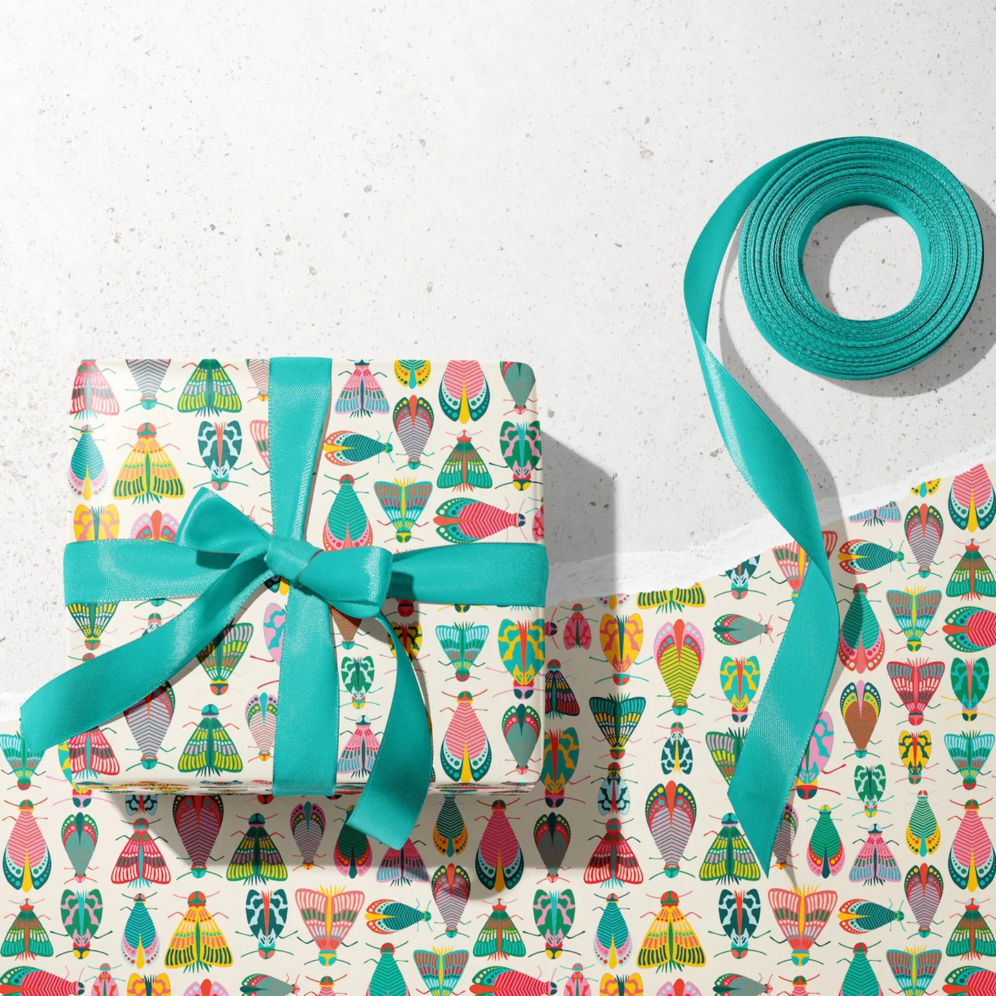 Spring Glow Wrapping Paper - Wrapped gift and roll of Spring Glow Wrapping Paper by Rebecca Jane Woolbright shown in a gift wrapping setup with teal ribbon