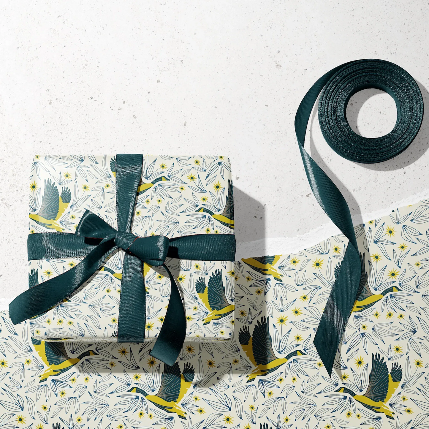 Wingspan Wrapping Paper - Wrapped gift and roll of Wingspan Wrapping Paper by Rebecca Jane Woolbright shown in a gift wrapping setup with teal ribbon