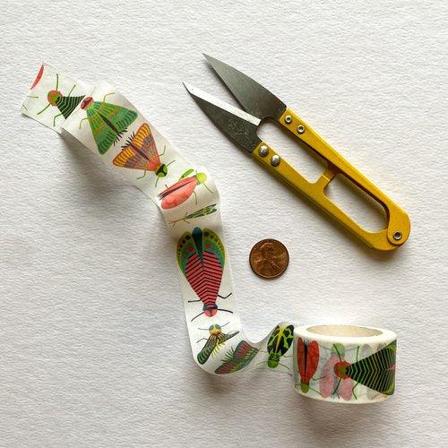 Mondo Bug washi tape roll unfurled on a white surface with colorful illustrated insects and small scissors.