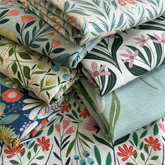 A variety of stacked floral tea towels on a counter