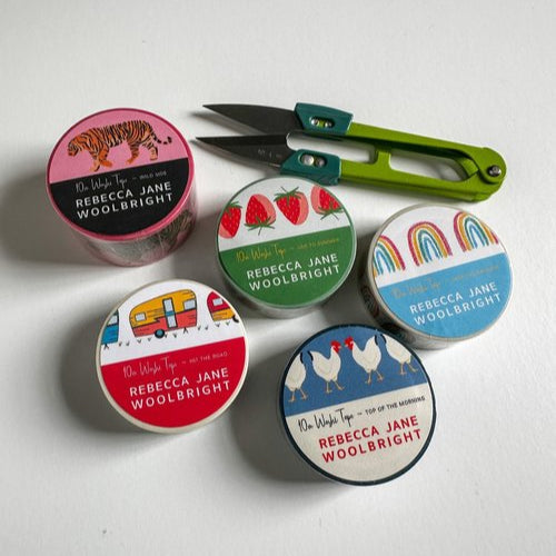 5 colorful rolls of washi tape with green scissors on white background