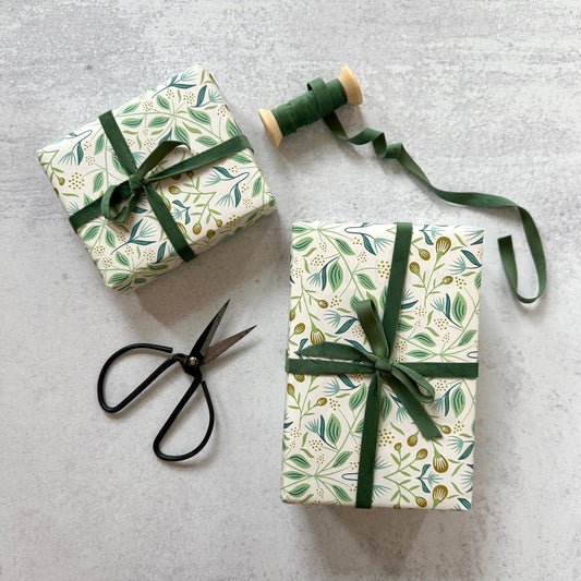green and blue floral wrapped gifts with green ribbon and scissors on a gray background