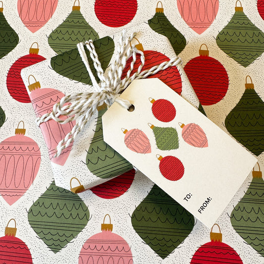 ornament print wrapped gift with gold and white string with coordinating gift tag on a background of the same patterned paper
