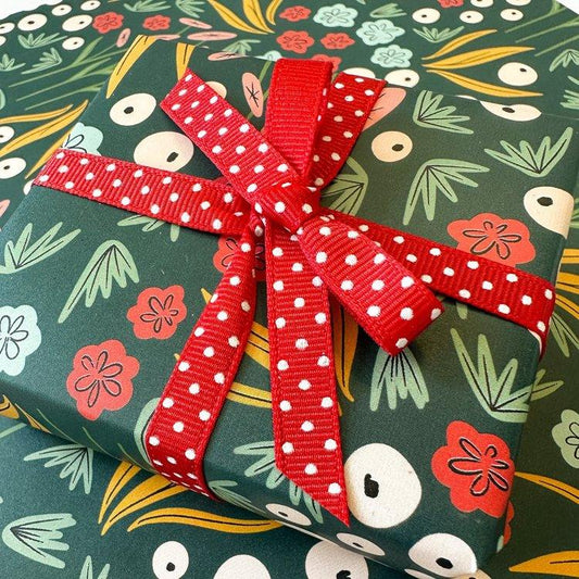 Green floral wrapped present with red bow with floral background
