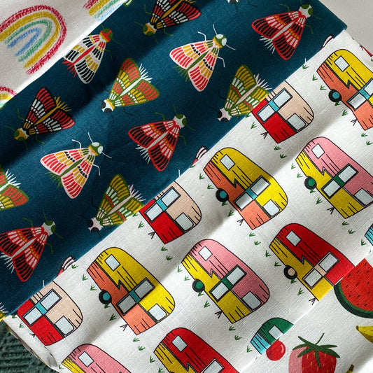 four different linen tea towels with rainbows, moths, fruit and camper vans