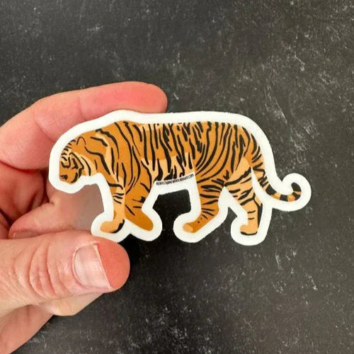 Tiger sticker being held by a hand against a black background