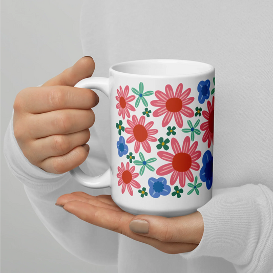 Colorful floral mug being held on a hand against a white background