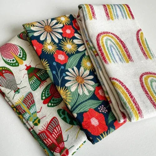 Three colorful linen tea towels with rainbows, moths and floral patterns hand illustrated by rebecca woolbright