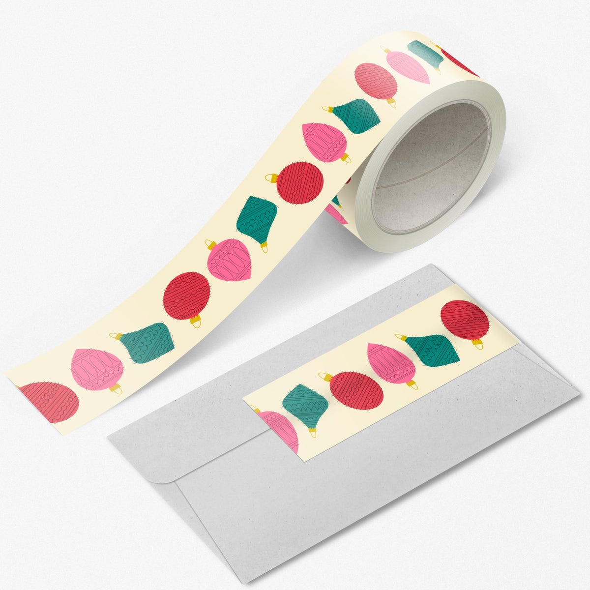 Retro Glam washi tape roll with vintage-style ornaments in pink, red, and green on a dark teal background by Rebecca Jane Woolbright, displayed next to a piece of paper with the tape applied to it.