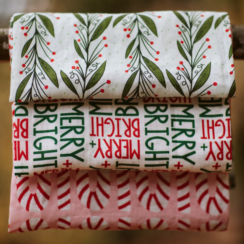 three holiday patterned kitchen towels hanging on a branch