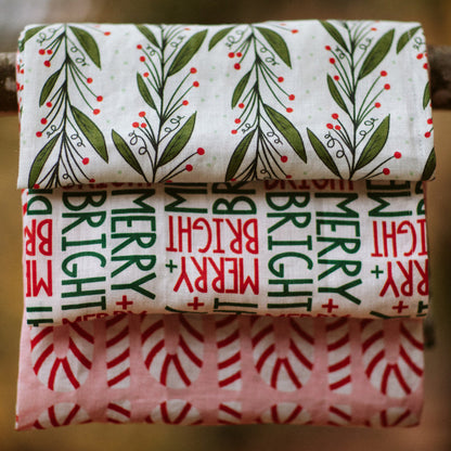 three holiday patterned kitchen towels hanging on a branch