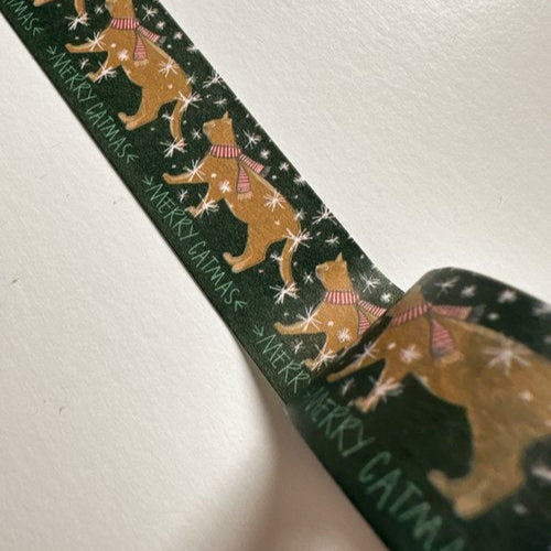 Close-up of Merry Catmas washi tape with festive cat illustrations and snowflake details on a deep green background.