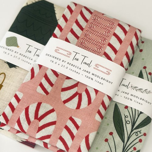 Merry Merry Tea Towel Bundle, three folded holiday tea towels in belly bands, a red and pink candy cane towel on top