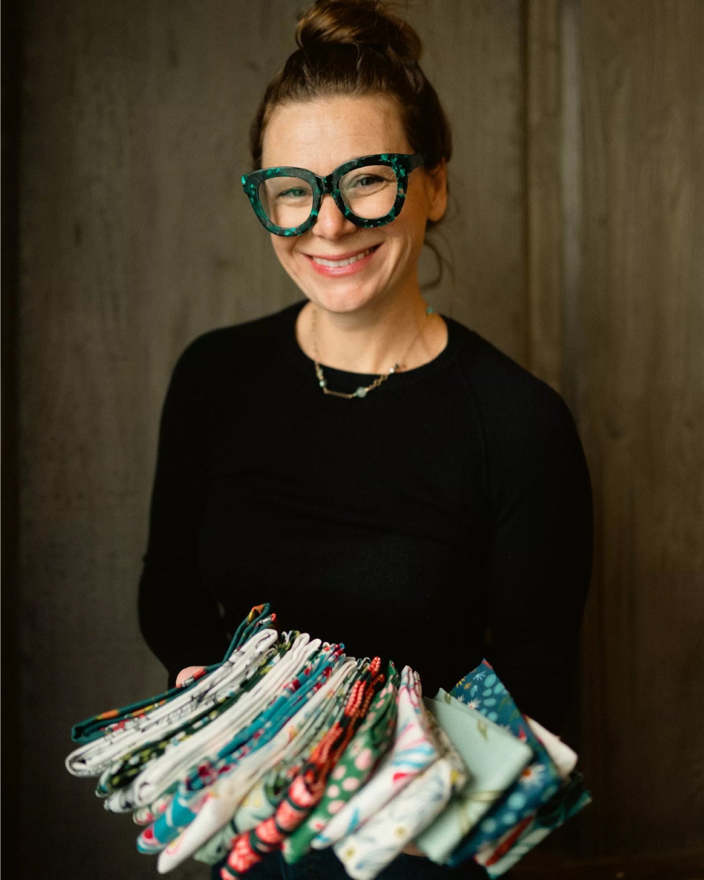 a woman in glasses holding tea towels
