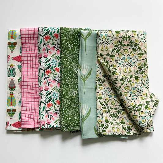 Six folded colorful tea towels with various patterns on a white background illustrated by Rebecca Woolbright