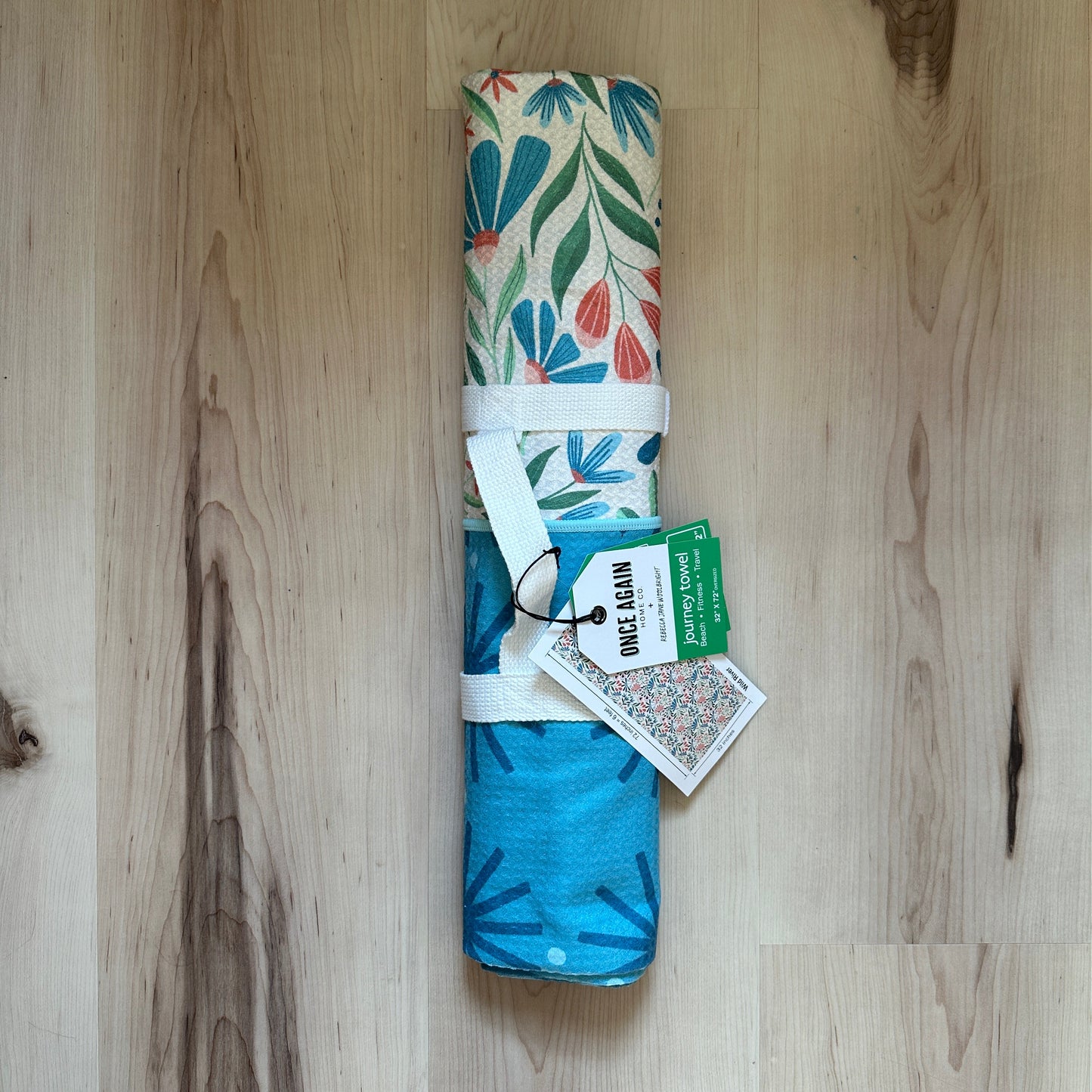 Rolled-up towel with floral and blue designs on a wooden floor