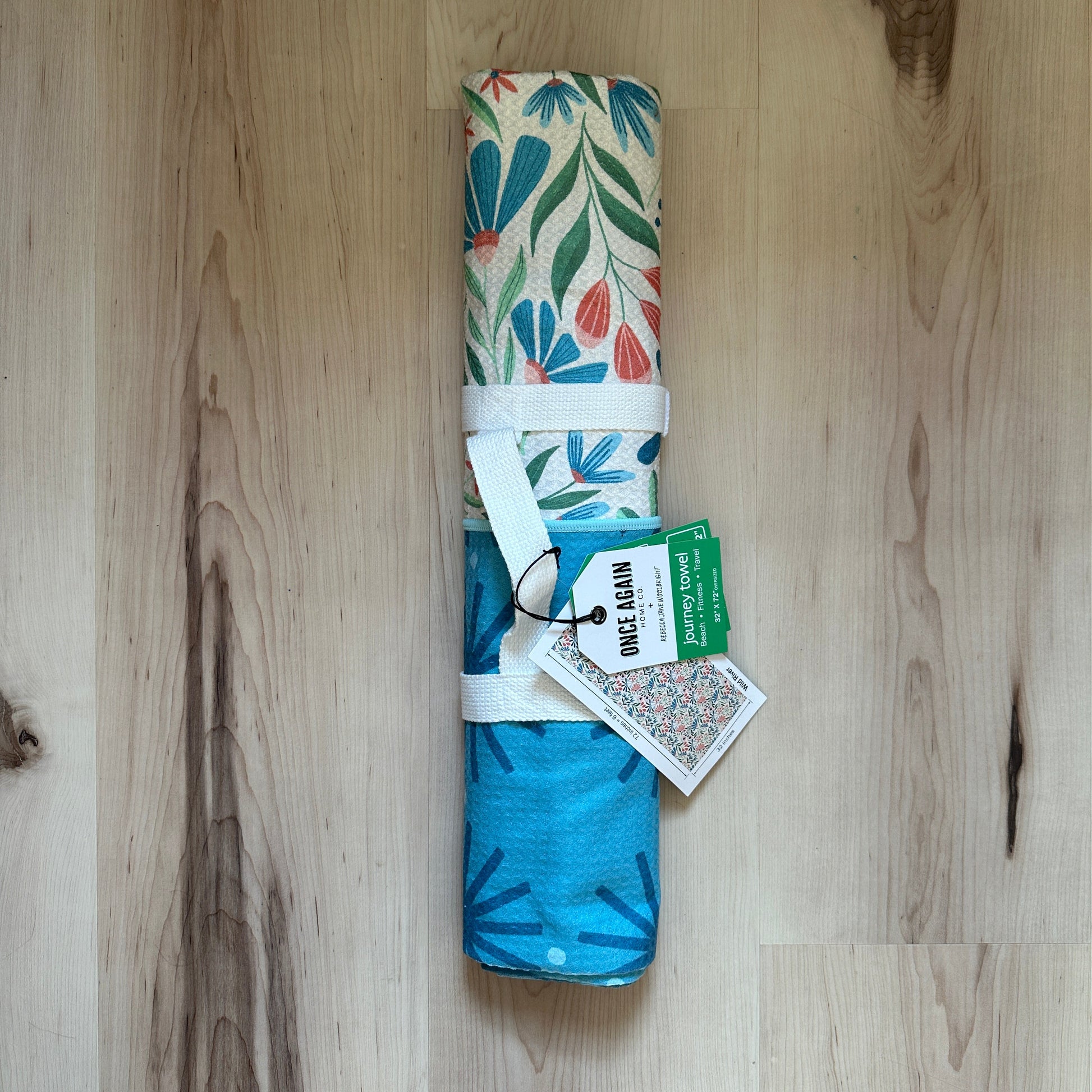 Rolled-up towel with floral and blue designs on a wooden floor