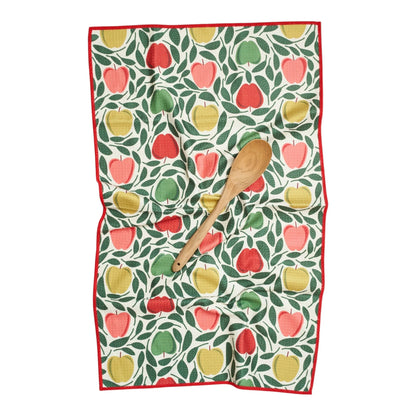 Kitchen towel with apple pattern and wooden spoon on a white background