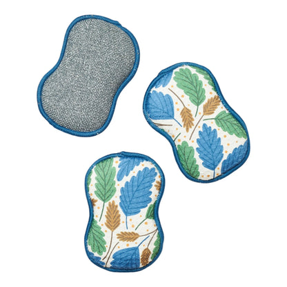 Two sponges with leaf pattern and one gray pad on a white background