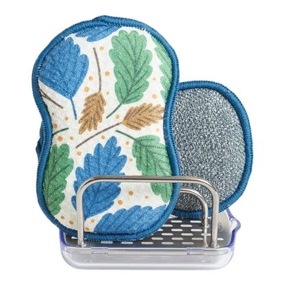 A reusable spongs on a clear plastic stand against a white background. One sponge has a blue, green, and tan leaf pattern on a white background, and the other is textured gray.
