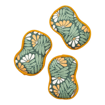 Three green and mustared leaf-patterned sponges on a white background