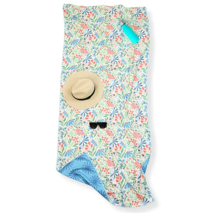 Floral patterned towel with a hat and sunglasses on top, on a white background